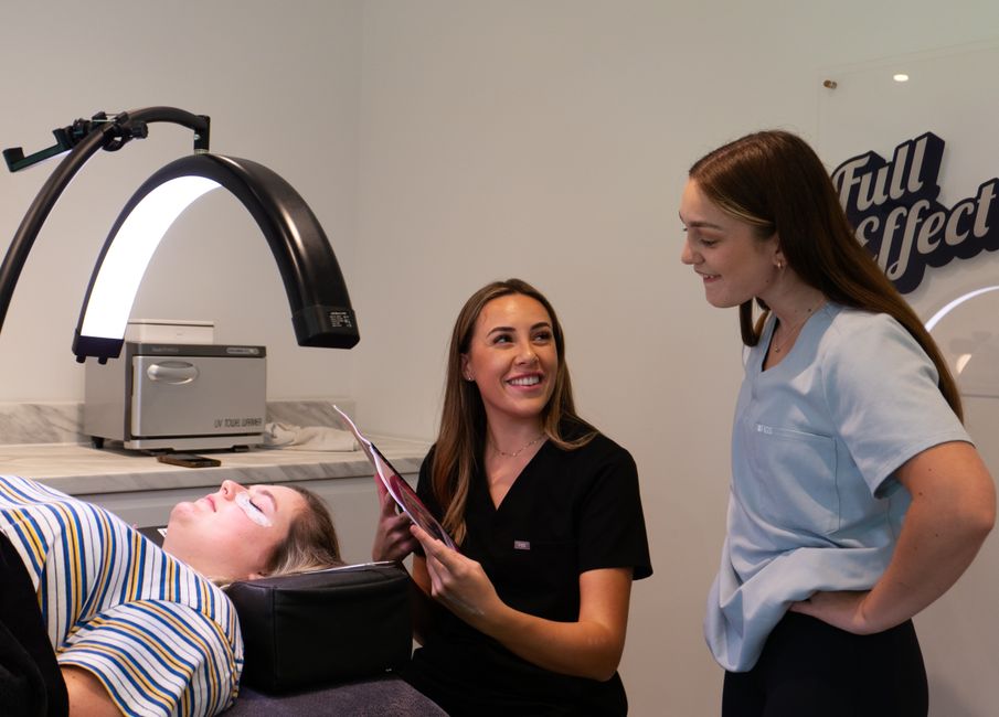 Two dermatologists consulting with a patient in a modern clinic, representing cosmetic and medical dermatology.
